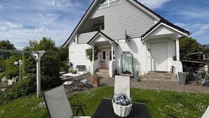 Une maison blanche avec une véranda, une table et des chaises à l’extérieur.