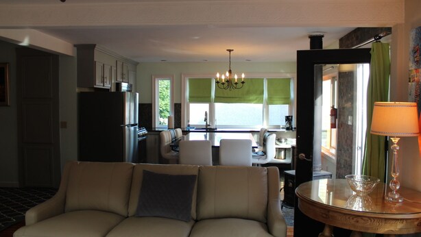 A modern living room with a sofa, a dining table, and a kitchen in the background.
