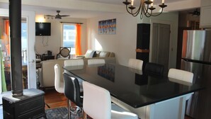 A modern kitchen with a central island, white chairs, a black countertop, and a chandelier.