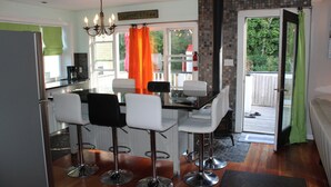 A modern kitchen with a dining area, featuring a chandelier, a sign reading "PROVINCETOWN", and a view of the outside.