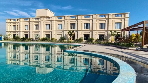 A large hotel with a swimming pool in front. - Gulmohar Royals (Cooch Behar)
