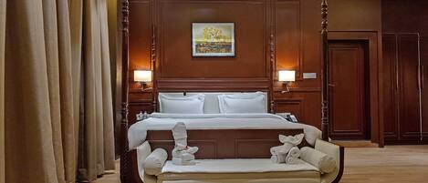 Une chambre d’hôtel avec un grand lit, un canapé, des boiseries et un tableau au mur.