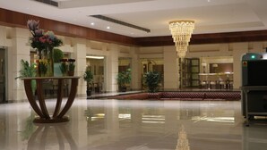 A spacious lobby with a reflective floor, a large chandelier, and a reception desk. - Gulmohar Royals (Cooch Behar)