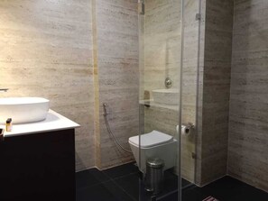 A bathroom with a glass-enclosed shower, a white sink, and a toilet.