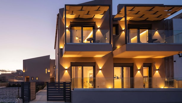 Ein modernes Mehrstöckgebäude mit Balkonen und großen Fenstern, das ein Flachdachdesign und einen begrenzten Eingang aufweist.