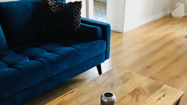 Un salon avec un canapé bleu, une table basse en bois ornée d’un vase décoratif et un tapis à motifs.