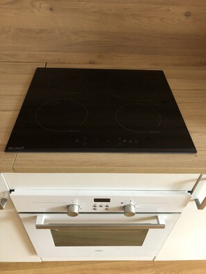 Een keuken met een zwart inductiekookveld en een witte oven.