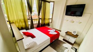 A hotel room with a bed, a TV, a bedside table, and a window with curtains. - Apartamento Frente a la Terminal Armenia Q (Armenia)