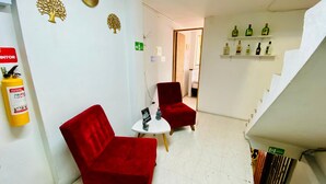 A hotel lobby with red chairs, a small table, a fire extinguisher, and shelves with bottles. - Apartamento Frente a la Terminal Armenia Q (Armenia)