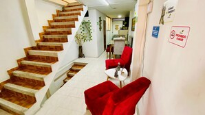 A staircase with wooden steps leading to a landing, a small table with a statue, red chairs, and a 'No Smoking' sign on the wall. - Apartamento Frente a la Terminal Armenia Q (Armenia)