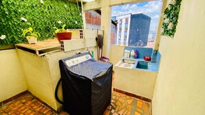 A small laundry area with a washing machine, a drying rack, and a window with a view of buildings. - Apartamento Frente a la Terminal Armenia Q (Armenia)