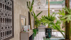 Un pasillo con suelo de baldosas, plantas en macetas y una reja decorativa.