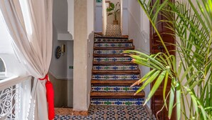 Una escalera con mosaicos de colores, barandilla blanca y una planta en maceta.