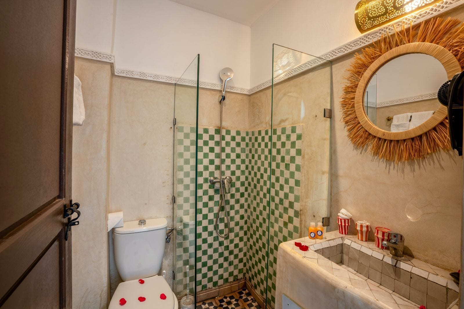 A bathroom with a checkered shower wall, a toilet, and a sink with a mirror.