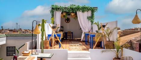 A rooftop terrace with a seating area, steps leading up to it, and a view of the cityscape.