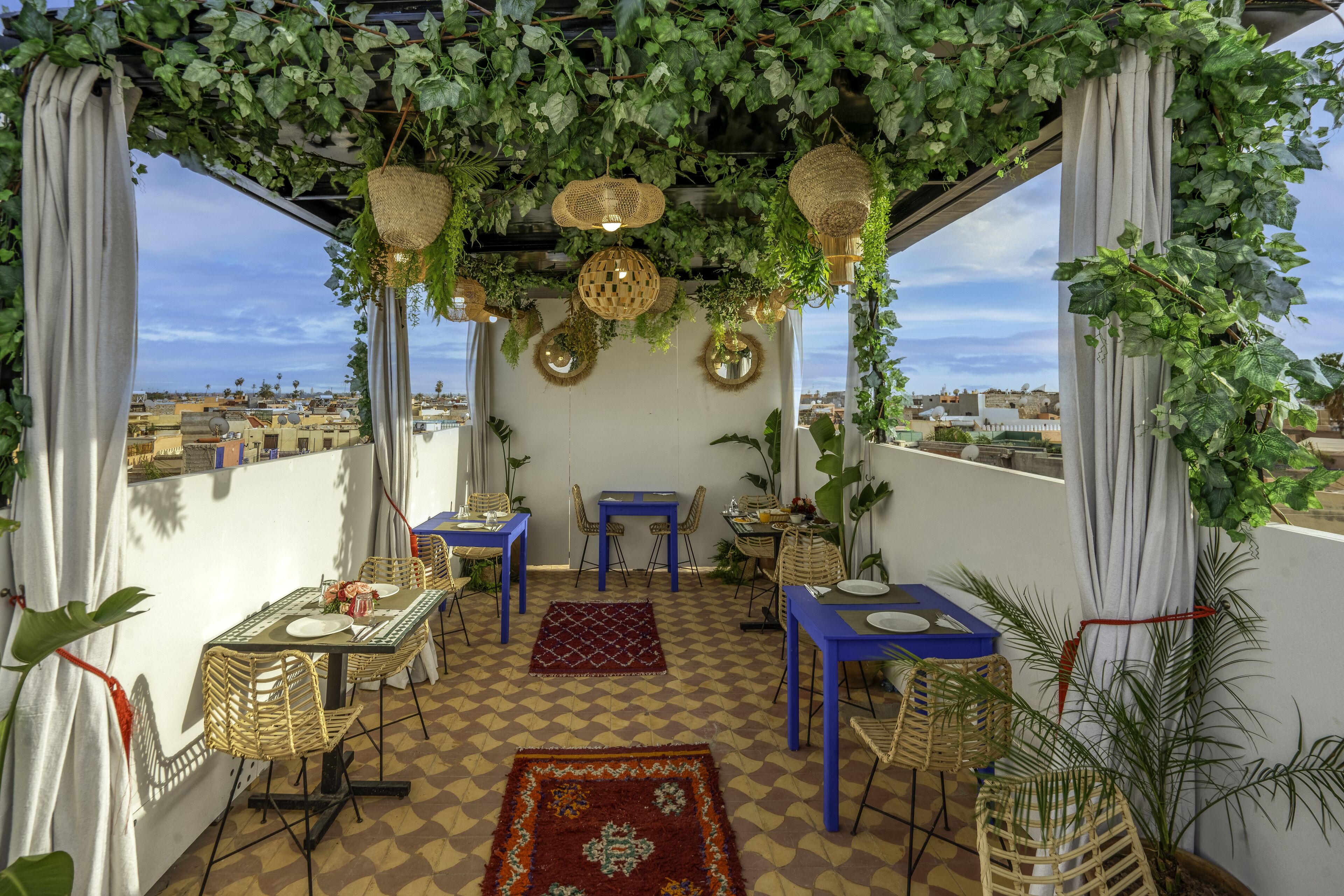 A terrace with tables and chairs, a checkered floor, and hanging baskets.
