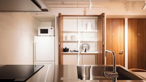 A modern kitchen with a built-in microwave, stainless steel sink, and wooden cabinets. - MANGA ART HOTEL BAKUROCHO (Tokyo)