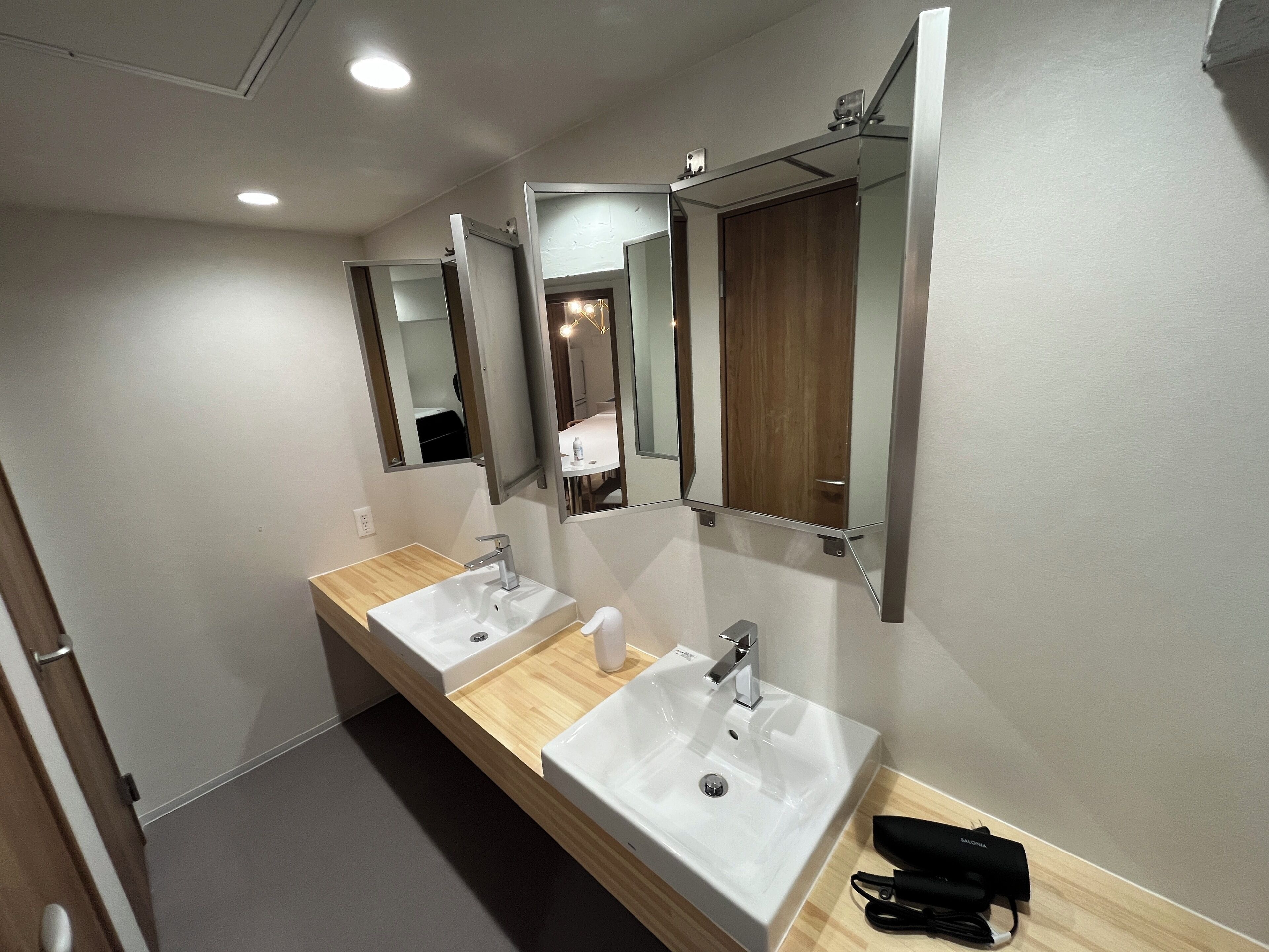 A modern bathroom with two sinks, a wooden vanity, and a mirror.