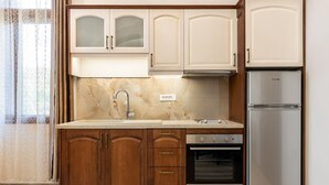 A kitchen with wooden cabinets, a stainless steel refrigerator, and an oven. - The Owl House - Studio #2 (Chania)