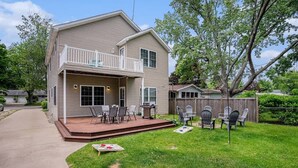 A two-story house with a covered front porch, a fenced backyard, and a tree. - Hounds on Hazel (South Haven)
