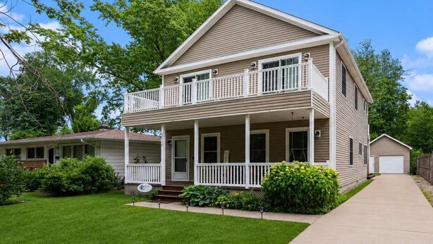 A two-story house with a front porch, a garage, and a well-maintained lawn. - Hounds on Hazel (South Haven)