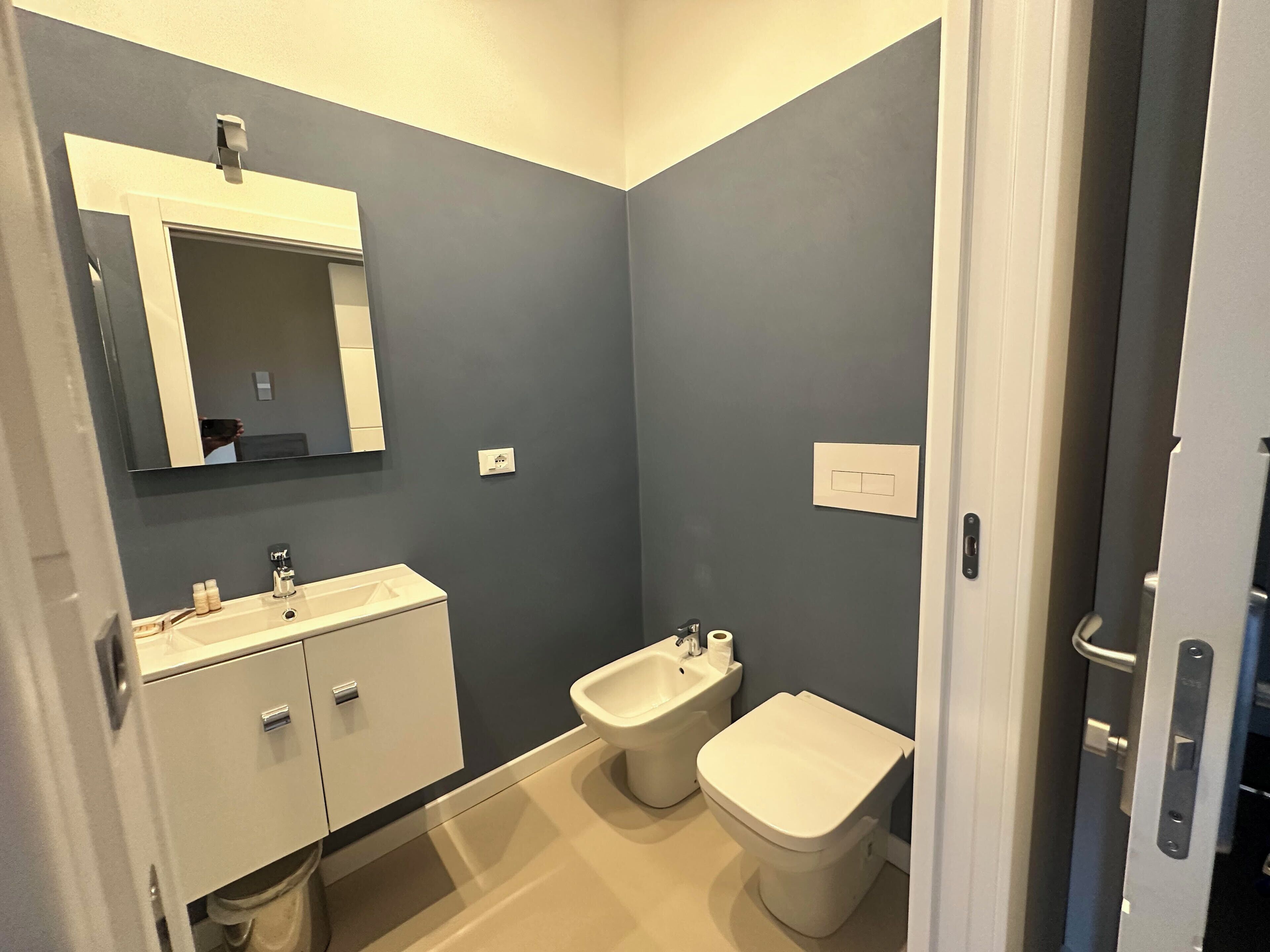 A compact bathroom with a white vanity, a bidet, and a toilet.