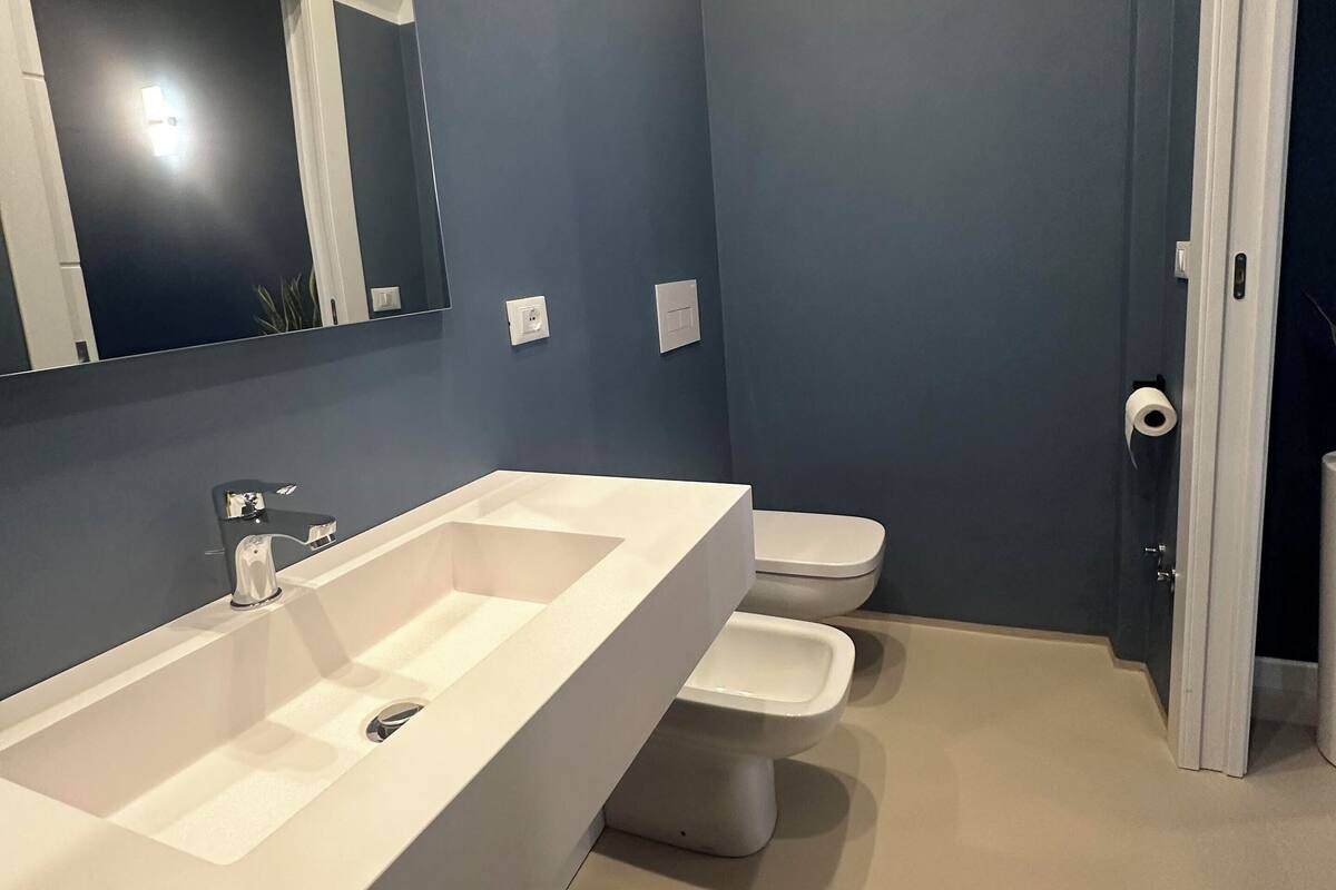 A bathroom with a white sink, two toilets, a mirror, and a door.