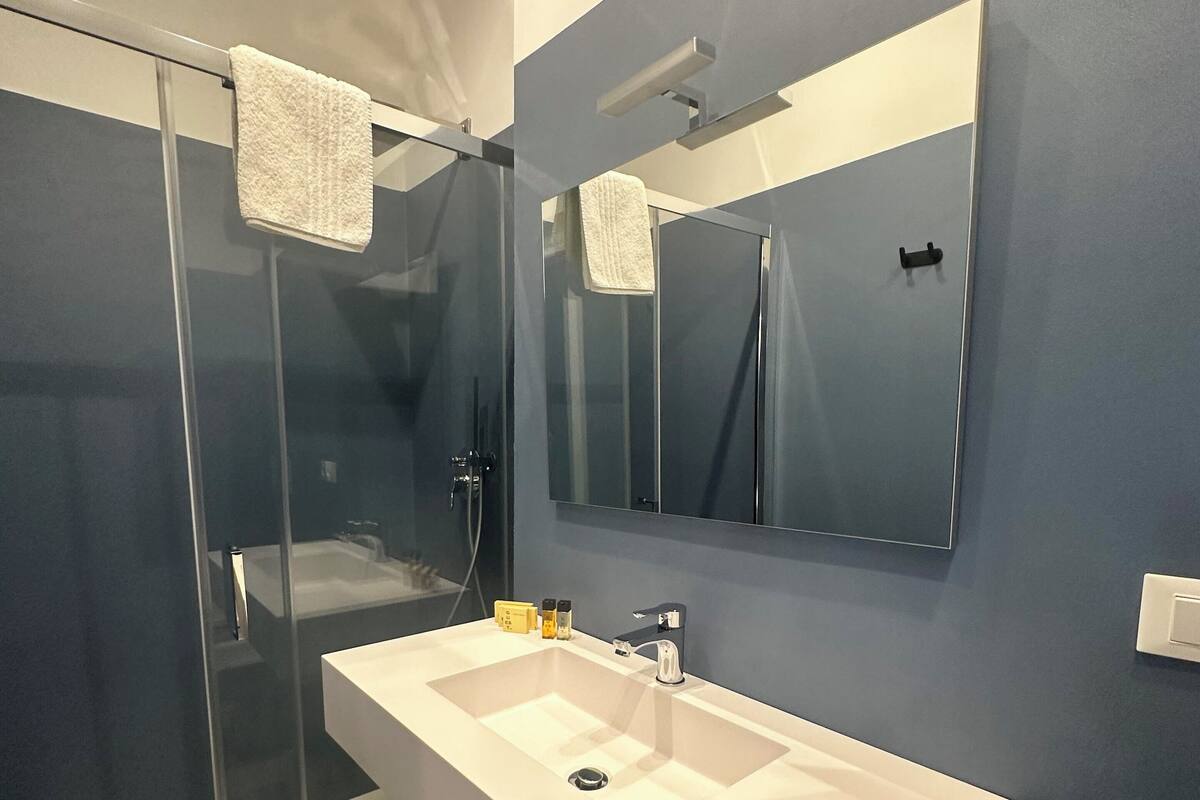 A modern bathroom with a white sink, a glass shower enclosure, and a large mirror.
