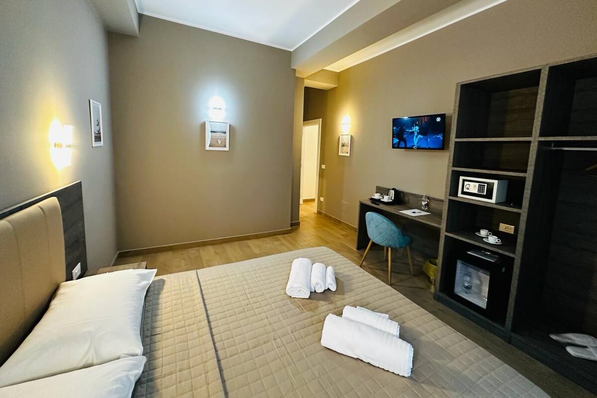 A hotel room with a bed, a desk, a television, and a wardrobe.