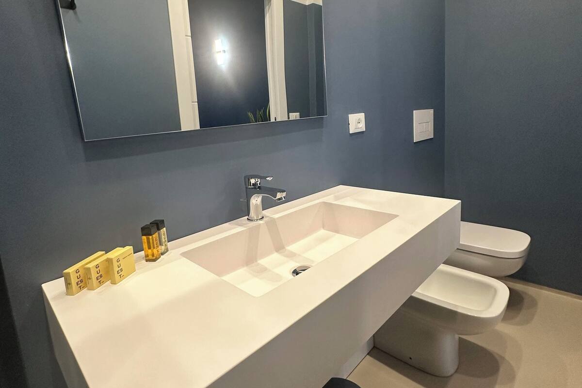 A modern bathroom with a large white sink, a mirror, and a toilet.
