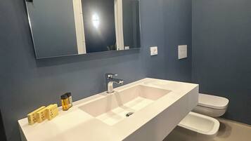 Un bagno moderno con un lavandino bianco ampio, uno specchio e un water.