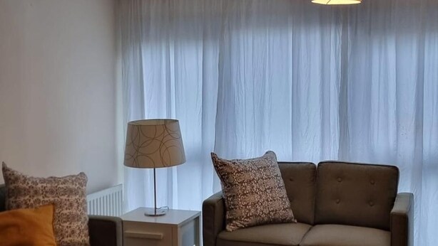 A modern living room with a sofa, a coffee table, and two pendant lights. - Stunning 2-bed Apartment Near Colindale Station (London)