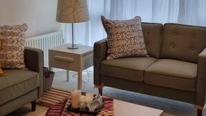 A living room with a sofa, a coffee table, a lamp, and a patterned rug. - Stunning 2-bed Apartment Near Colindale Station (London)