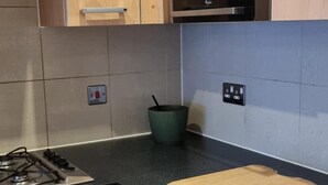 A kitchen with wooden cabinets, a black countertop, a stove, and an oven. - Stunning 2-bed Apartment Near Colindale Station (London)
