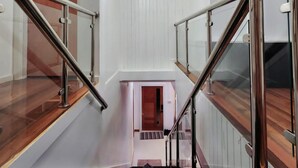 A modern staircase with glass railings and wooden steps leading to a door. - Little Heaven - Remarkable Spot in Georgetown (Georgetown)