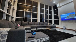 A modern living room with a sectional sofa, a flat-screen TV mounted on the wall, and large windows providing natural light. - Little Heaven - Remarkable Spot in Georgetown (Georgetown)