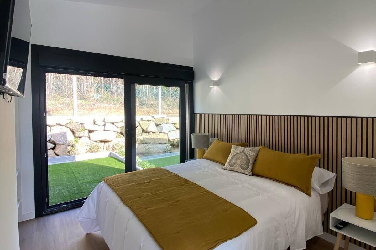 Une chambre moderne avec un grand lit, une porte-fenêtre coulissante donnant sur une terrasse et un plancher en bois.