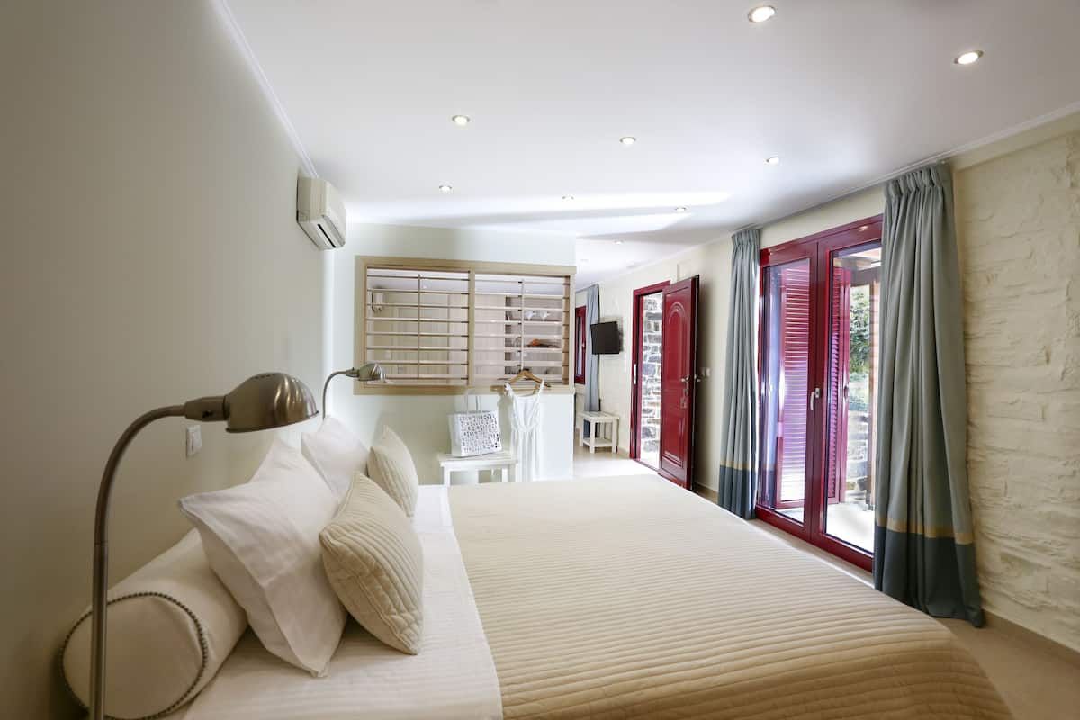 A hotel room with a large bed, a desk, a chair, and a wardrobe.