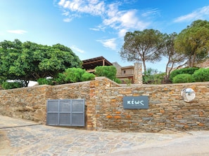 A stone wall with a sign reading 'KEWC by the sea' and a metal gate.