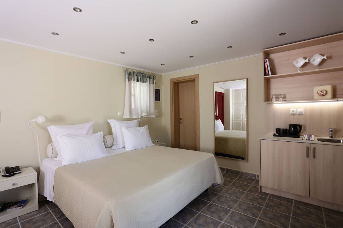 A hotel room with a bed, bedside table, lamp, and a small cabinet with a mirror.