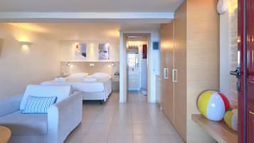 A hotel room with two beds, a sofa, a wooden wardrobe, and a small seating area.