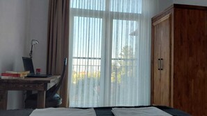 A room with a bed, a desk with a laptop, a chair, and a wooden wardrobe.