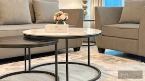 A modern living room with a sofa, two round tables, and a vase of flowers.