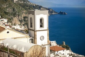 A coastal town with a prominent clock tower, a church, and a view of the sea.
