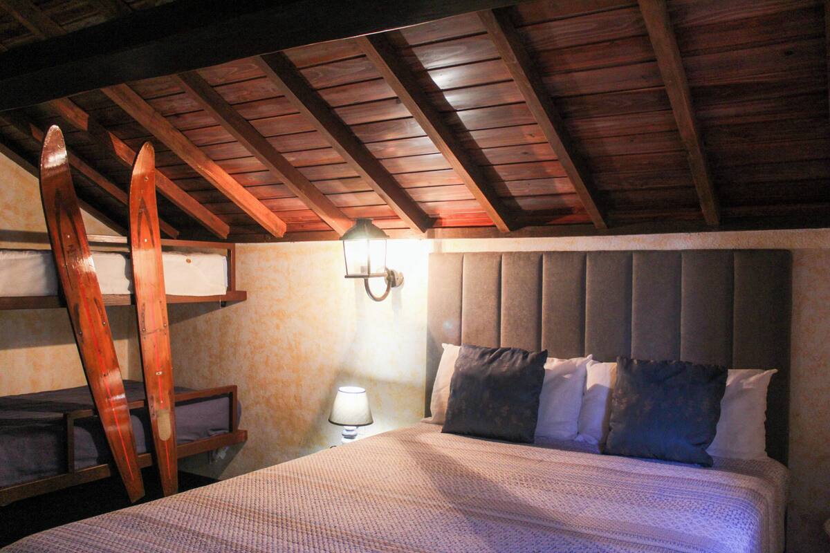 Une chambre à coucher avec un plafond en bois, un lit doté d’une tête de lit et une table de chevet avec une lampe.