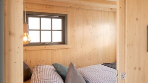 A wooden cabin room with a bed, pillows, and a window. - Märchenhaftes Tiny Haus auf dem Historischen Gut Junkernhof in der Grimm Heimat (Calden)
