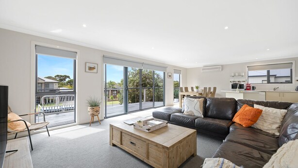 A modern living room with a leather sofa, a wooden coffee table, and a dining area with a table and chairs. - Beachside Escape in Cowes (Cowes)