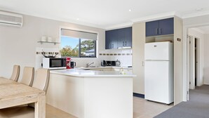 A modern kitchen with a central island, white cabinetry, and a built-in microwave. - Beachside Escape in Cowes (Cowes)