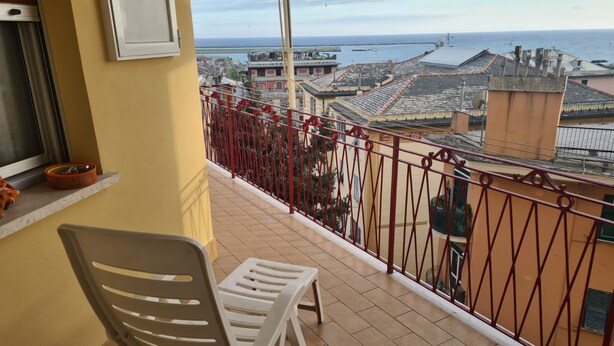 A balcony with a view of the sea and buildings.