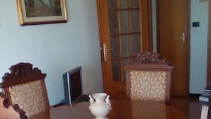 A dining room with a wooden table and chairs, a vase, and a door with glass panels.